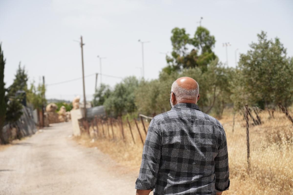 un palestino camina por una carretera recientemente arreglada hacia sus campos de cultivo